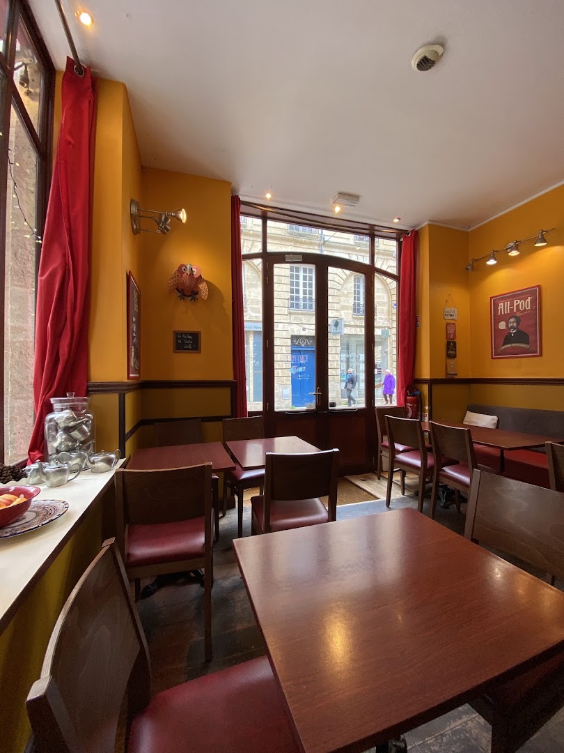 La salle jaune et rouge du Bocal avec tables en bois et rideaux rouges
