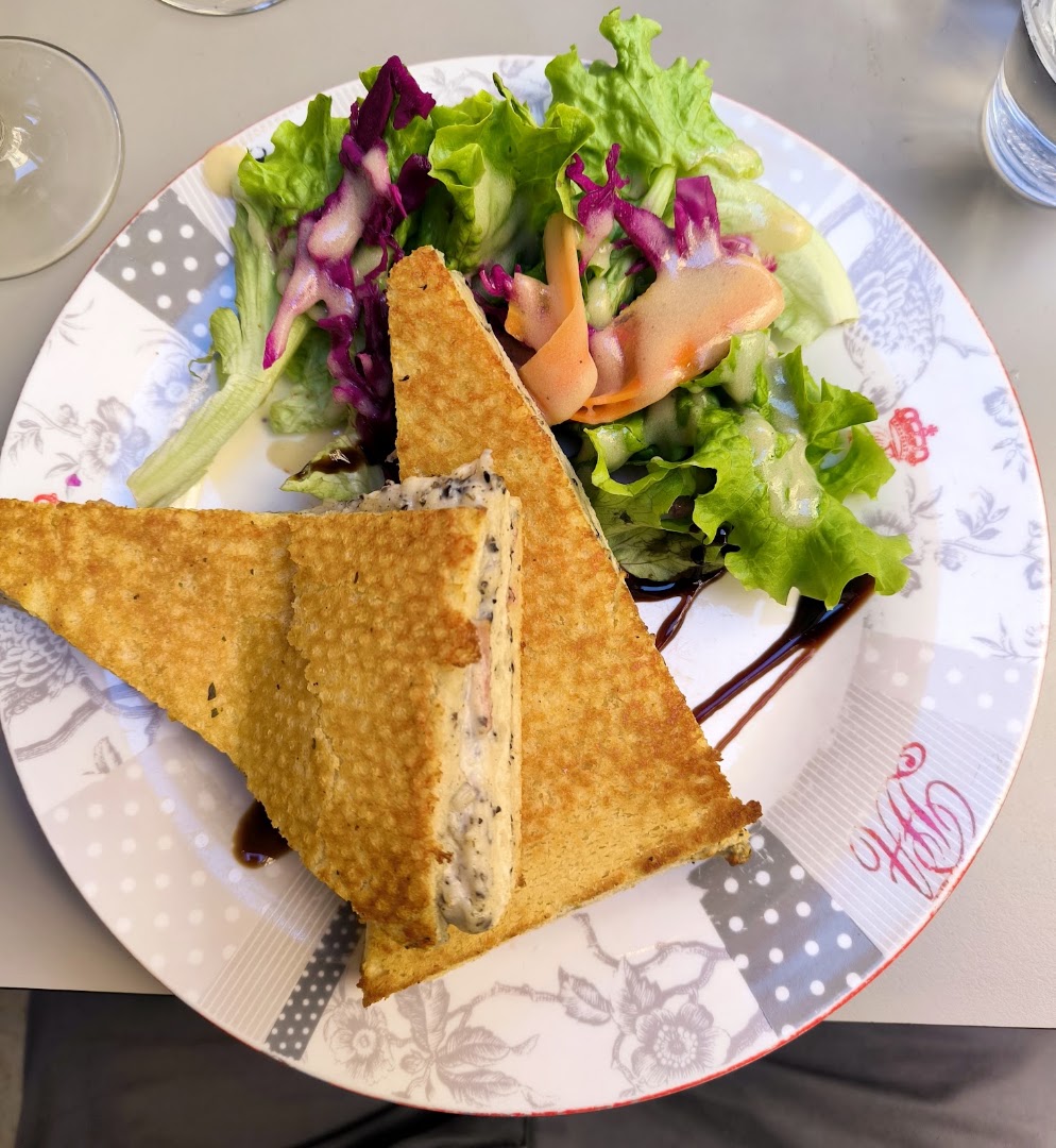 Un sandwich grillé triangulaire accompagné d’une salade colorée